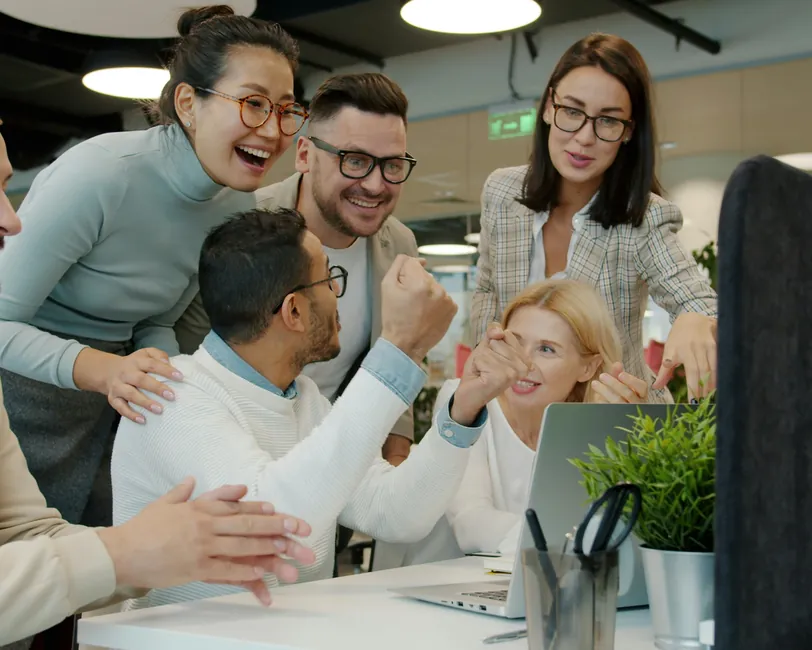 A diverse team celebrating around a desk